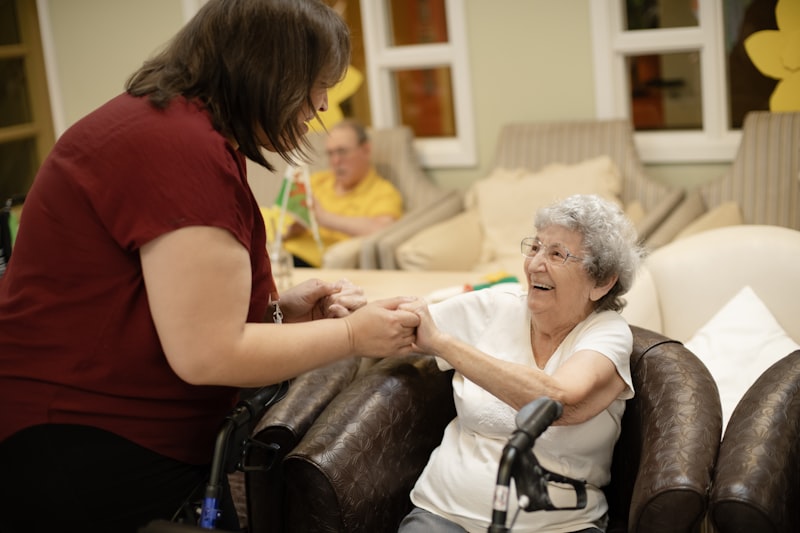 A Nightingale Caregiving caregiver holding hands warmly with a laughing elderly client